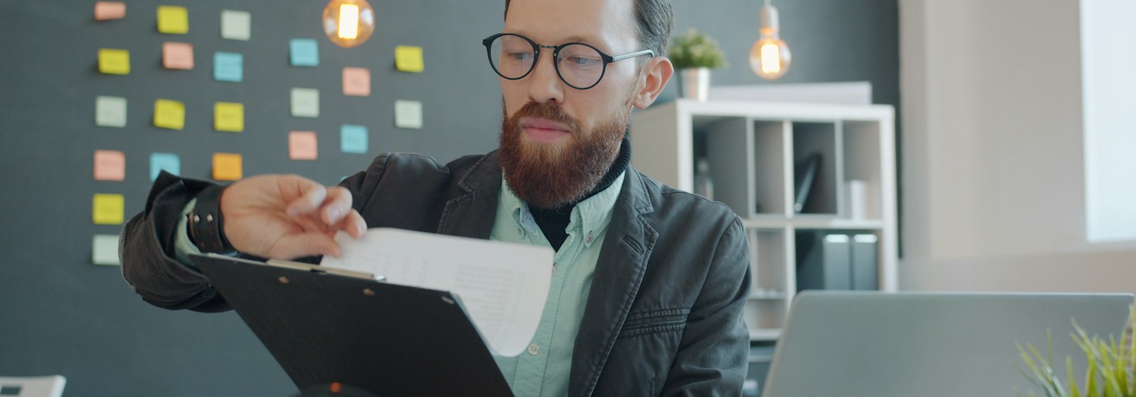 Mann mit Brille prüft Unterlagen am Schreibtisch