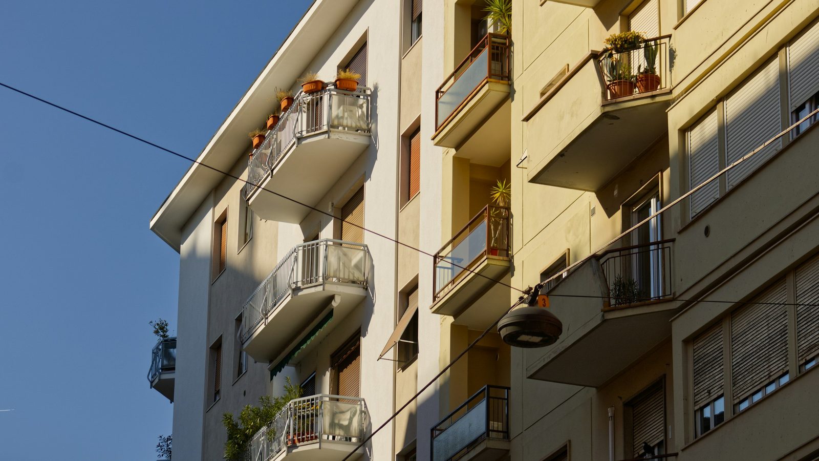 Wohnhaus mit Balkonen und Blumentöpfen in der Sonne