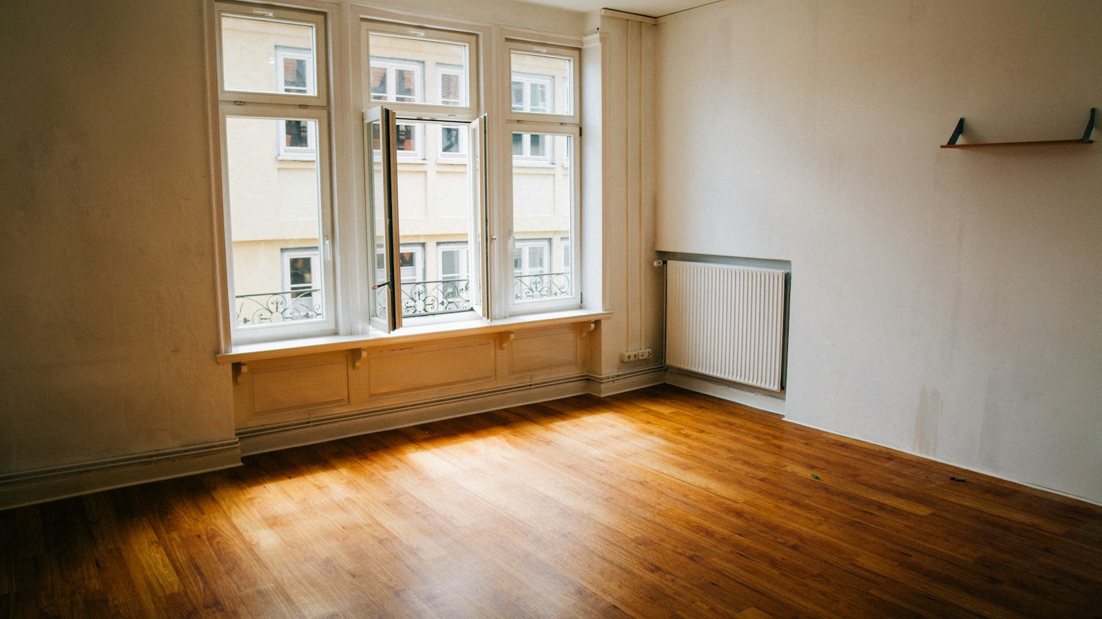 Leerer Wohnraum mit Holzboden und großem Fenster