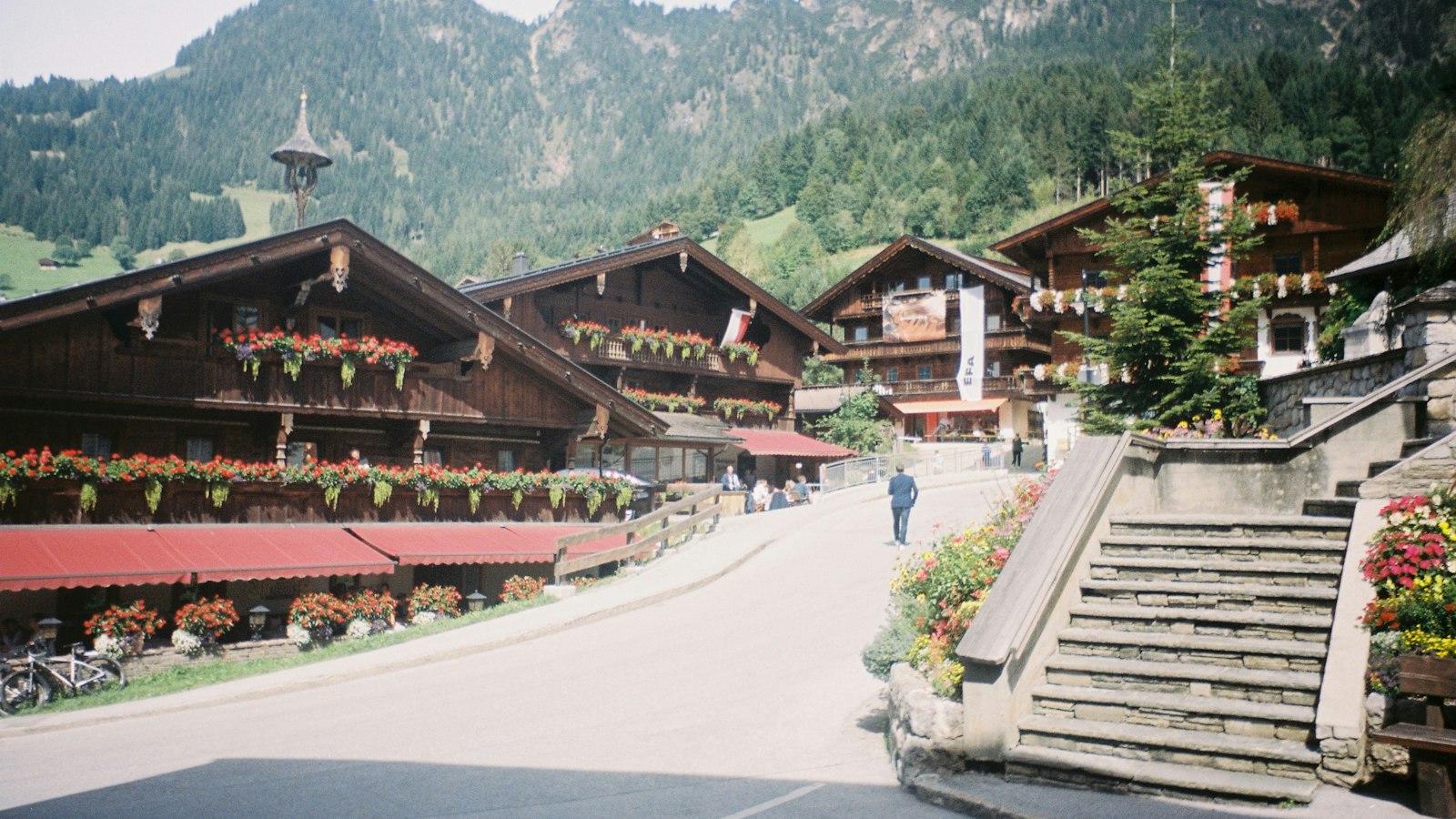 Dorfstraße mit traditionellen Häusern vor Bergpanorama
