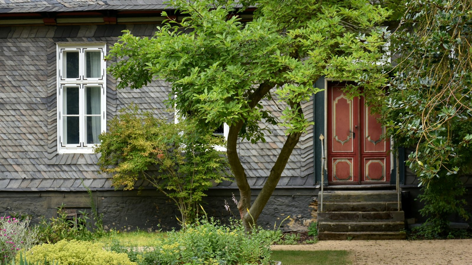 Altes Haus mit roter Eingangstür und Garten