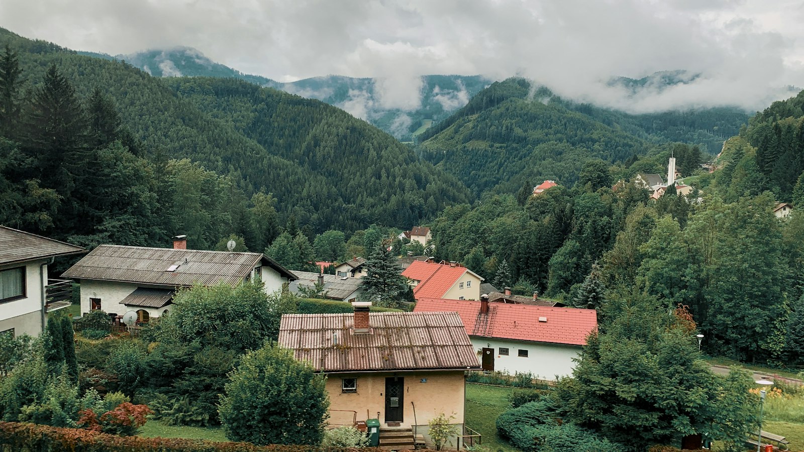 Einfamilienhaus mit Garten vor bewaldeten Bergen