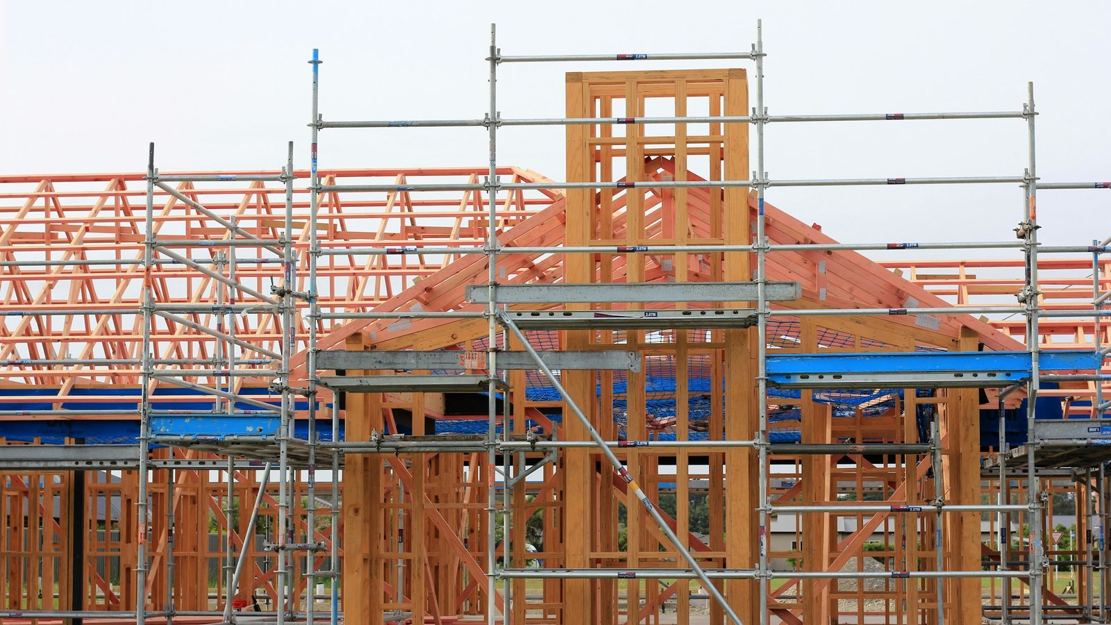 Neubau mit hölzernem Dachstuhl hinter einem Baugerüst