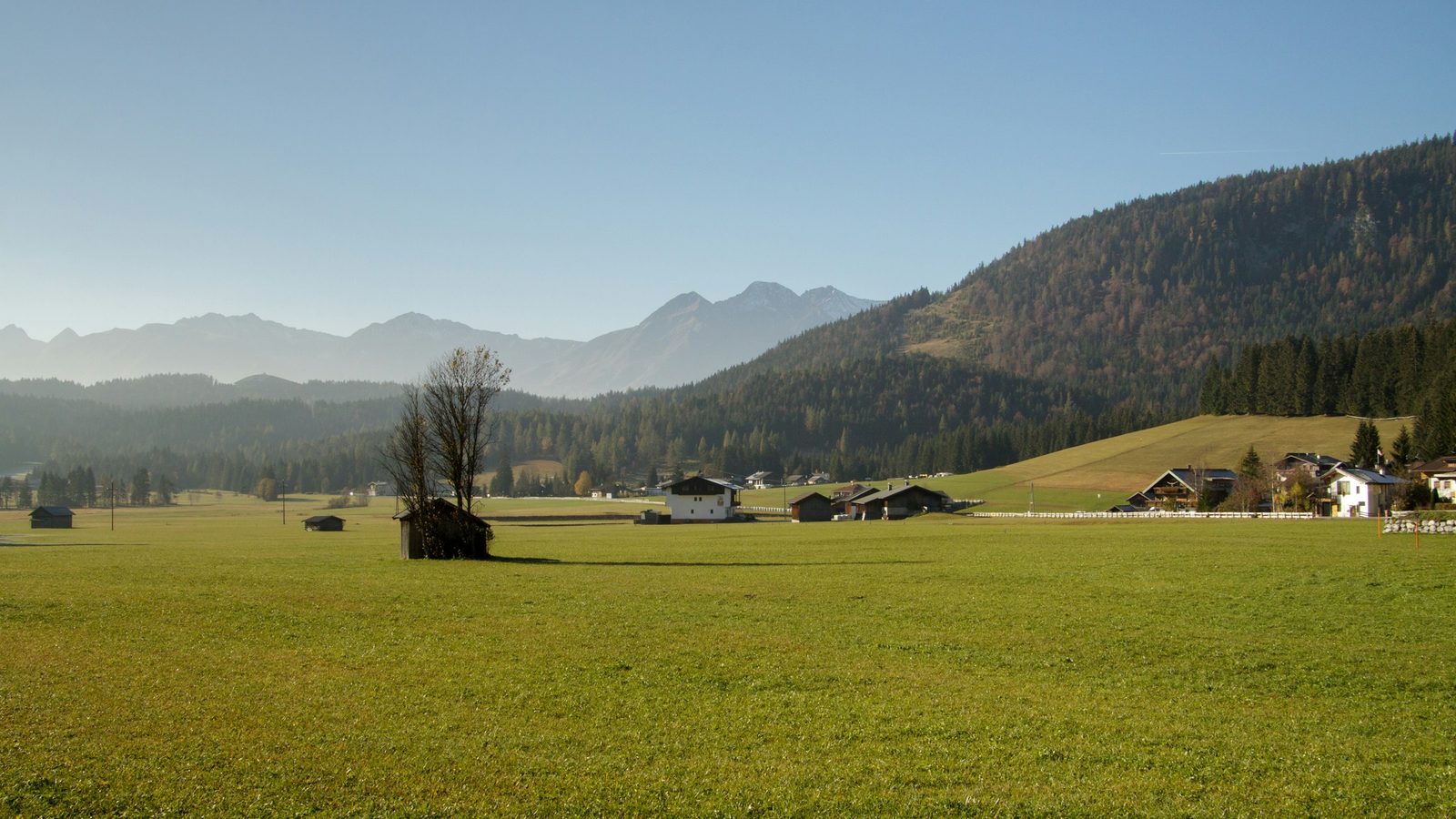 Wiese am Ortsrand mit Bergkette im Hintergrund